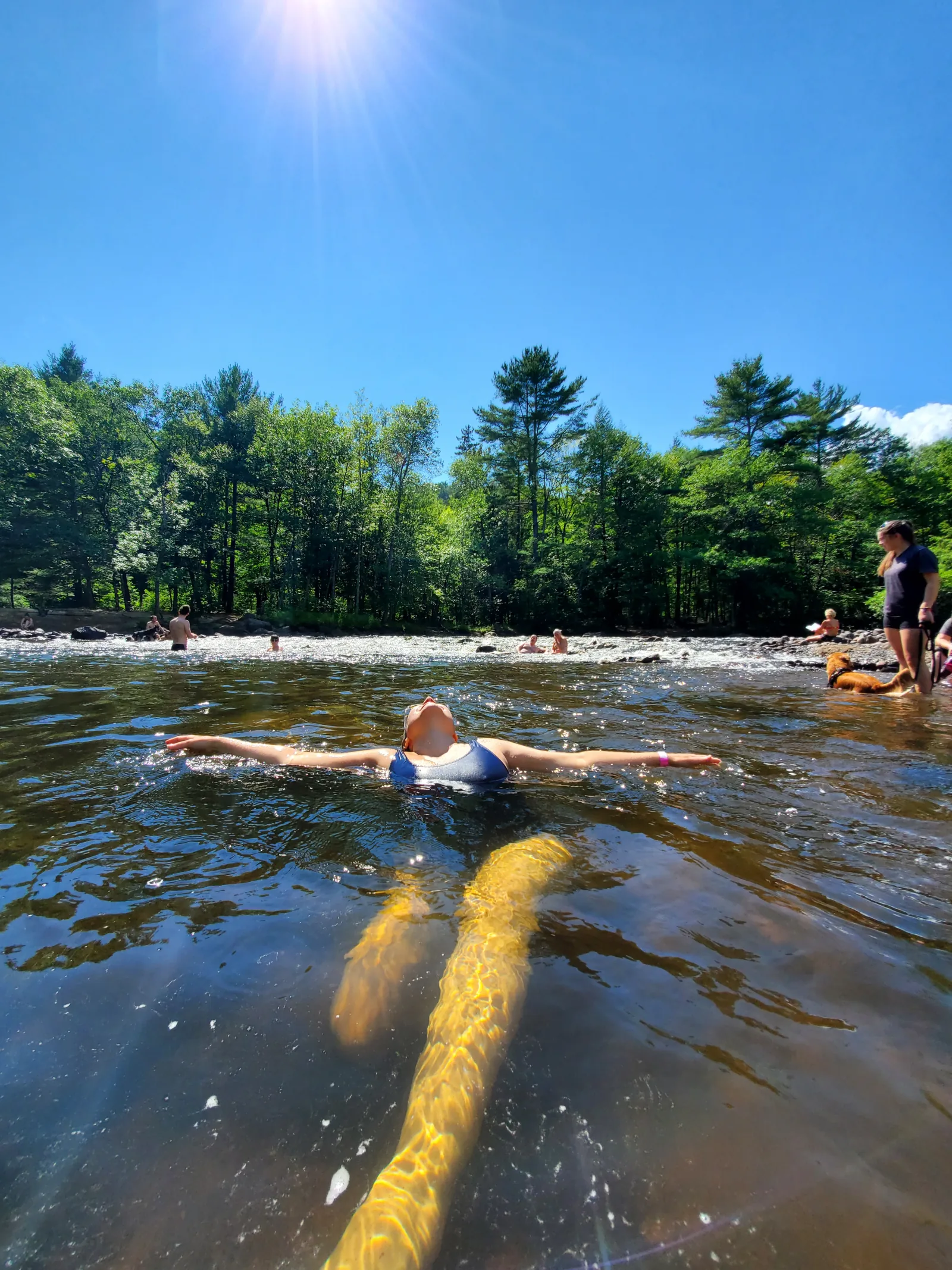 Alice flotando con los brazos abiertos en el río Maskinongé durante un día soleado de 2020