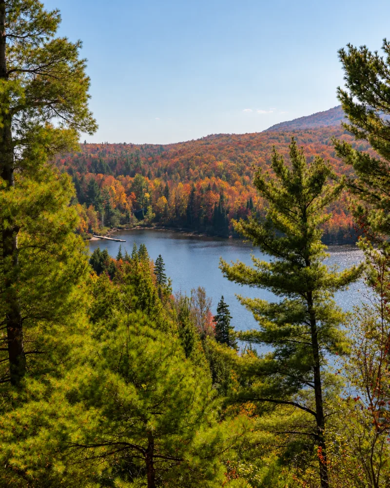 Vista do lago e das montanhas coloridas entre os pinheiros no Parc national du Mont-Orford