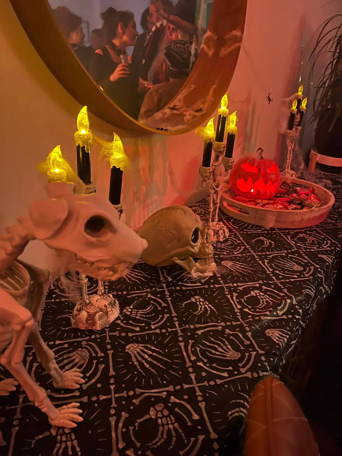 Decoración de Halloween en casa: candelabros de esqueleto con velas LED, calavera y calabaza sobre la bandeja de dulces